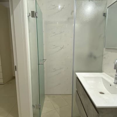 מקלחון זכוכית עם דלת פתוחה וחיפוי קיר שיש