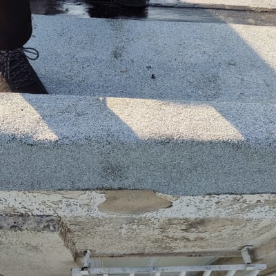 אדם עומד על גג עם חומר איטום שחור