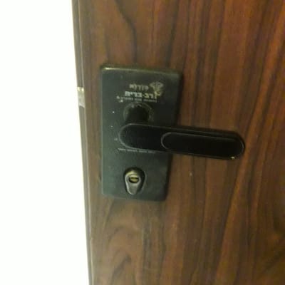 מנעול דלת עם ידית שחורה על דלת עץ