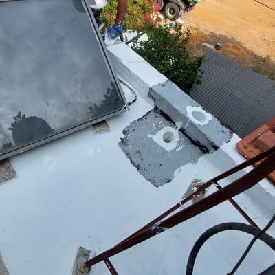 אדם מורח חומר איטום על גג ליד קולטן שמש