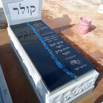 מצבה עם כיתוב בעברית ואבנים כחולות