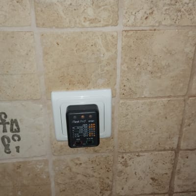 בודק שקע חשמלי מחובר לשקע בקיר