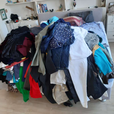 בגדים מסודרים בערימה על מיטה בחדר שינה