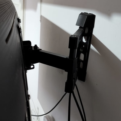 זרוע מתכתית מחזיקה טלוויזיה על קיר לבן