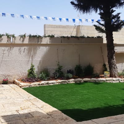 גינה עם דשא מלאכותי, עצים ופרחים