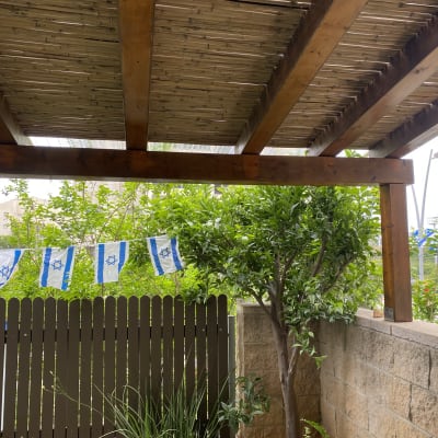 פרגולה מעץ עם דגלים כחול לבן בגינה