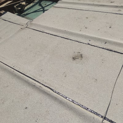 איטום גג עם חומר שחור בין לוחות בטון