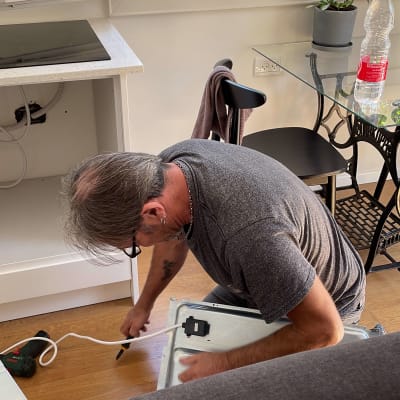 אדם מתקין כיריים חשמליות עם כבל חשמל וכלי עבודה