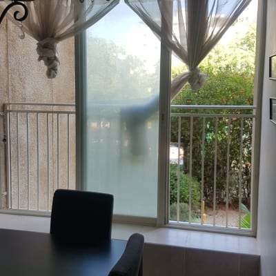 חלון עם וילונות קשורים ומעקה מתכת