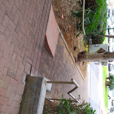 מעקה מתכת לאורך שביל מרוצף בלבנים אדומות