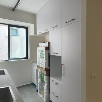 ארונות מטבח לבנים עם ידיות מתכת, חלון גדול