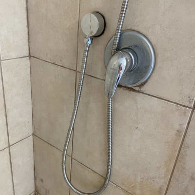 ברז מקלחת עם צינור מתכת על קיר אריחים