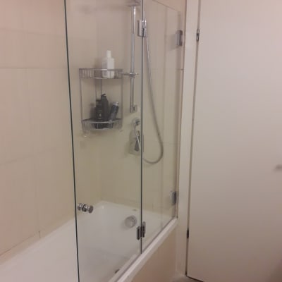 מקלחת עם דלת זכוכית ומדף מוצרים