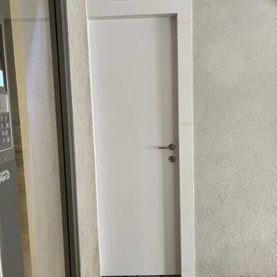 דלת לבנה עם ידית מתכת על קיר בטון