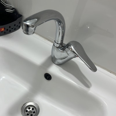 ברז כרום מעל כיור לבן עם ניקוז