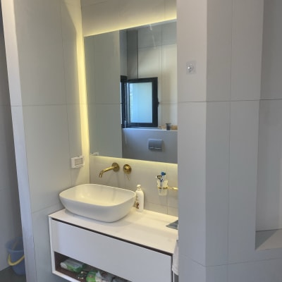 כיור לבן עם ברזים מוזהבים בחדר אמבטיה משופץ