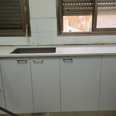 מטבח עם ארונות לבנים וכיור מתכת