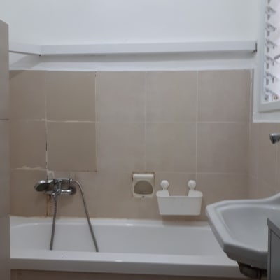 קיר צבוע בלבן מעל אריחי אמבטיה