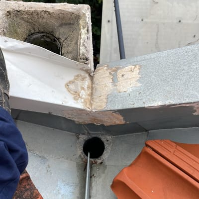 צינור מתכת נכנס לפתח ניקוז בגג