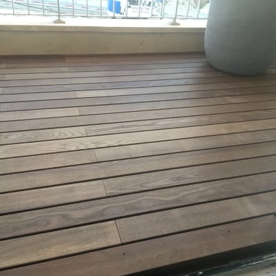 רצפת דק עץ חום עם עציץ גדול בפינה