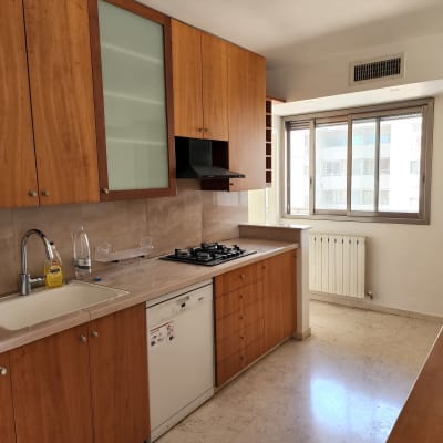 מטבח עם ארונות עץ, כיור וברז, בקבוקי מים