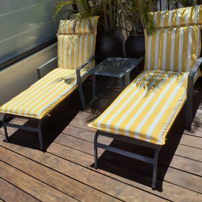 כריות פסים צהובות על כיסאות נוח במרפסת