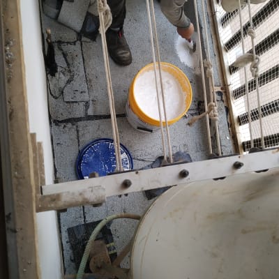 אדם מורח חומר איטום לבן על גג עם מברשת