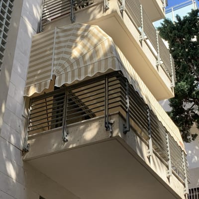 סוכך פסים לבן וצהוב על מרפסת בניין