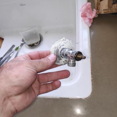 יד מחזיקה ברז עם חומר איטום ליד כיור