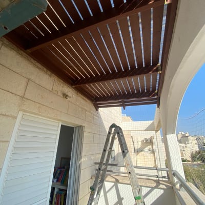 פרגולה מעץ מותקנת במרפסת עם סולם מתכת