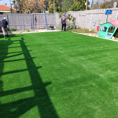 שני אנשים עובדים על דשא סינתטי בגינה