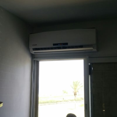 מזגן מותקן מעל חלון עם אדם לידו