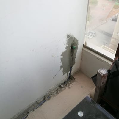 קיר עם תיקון טיח וצינור חשוף ברצפה