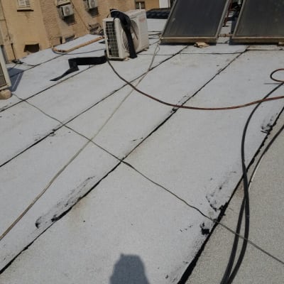 גג עם יריעות איטום, צינורות וצל של אדם