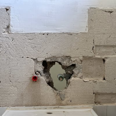 קיר עם חור וצינורות חשופים בשיפוץ