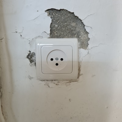 שקע חשמלי בקיר עם טיח מתקלף
