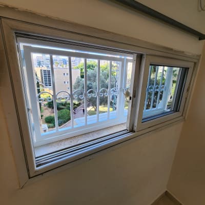 חלון עם מסגרת לבנה וסורגי מתכת