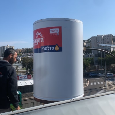 דוד שמש מותקן על גג עם אדם לידו