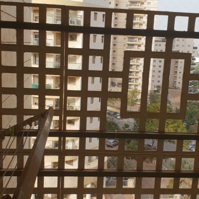 רשת יונים מותקנת על מרפסת עם בניינים ברקע