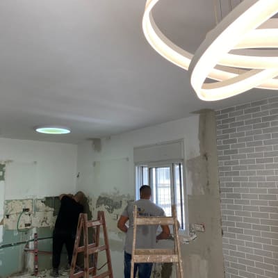 שני אנשים עובדים על קיר במהלך שיפוץ