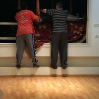 שני אנשים מעבירים רהיט דרך חלון פתוח