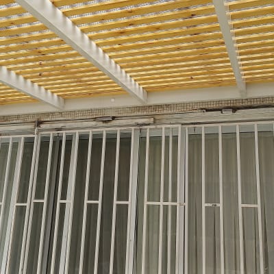 פרגולה מאלומיניום עם קורות עץ מעל חלון