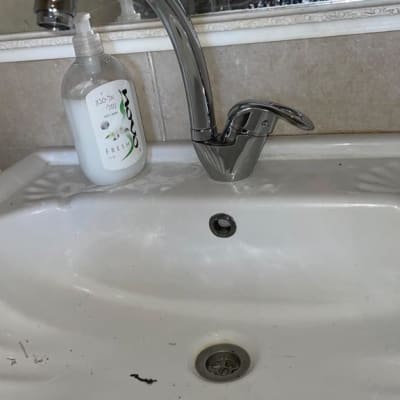 ברז כיור עם סבון נוזלי ומראה מלוכלכת