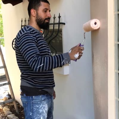 אדם צובע קיר חיצוני עם רולר צבע