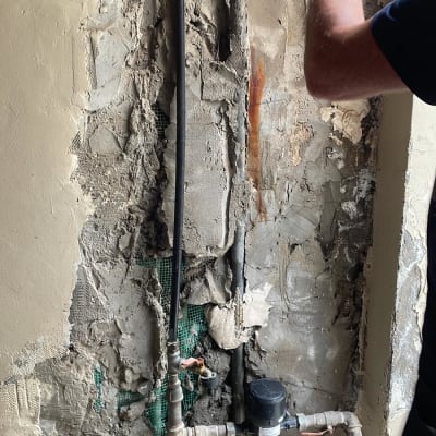 צנרת מים חשופה בקיר עם מד מים