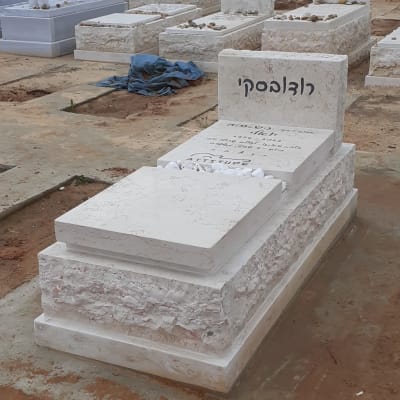 מצבות לבנות עם שמות ואבנים קטנות מונחות עליהן