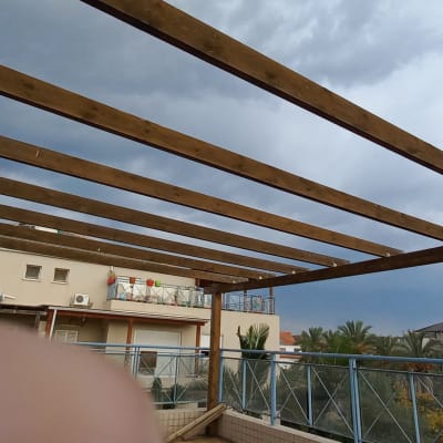 קורות עץ על גג מרפסת עם שמיים מעוננים