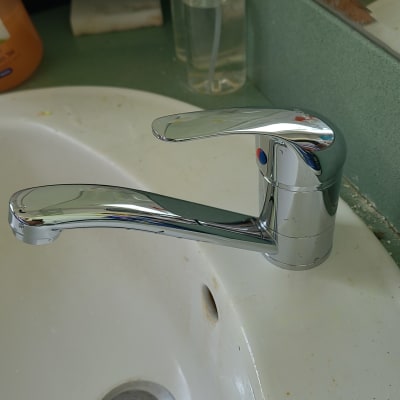 ברז כרום על כיור לבן עם כתמים