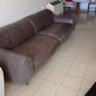 ספה חומה גדולה בחדר עם רצפת אריחים