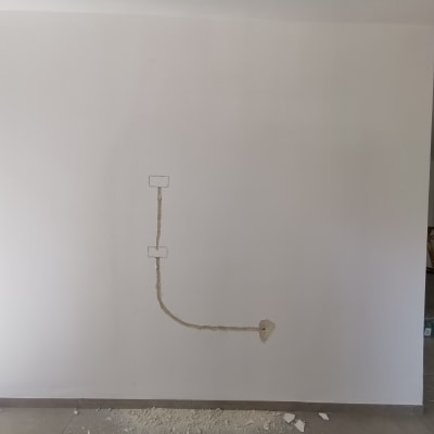 קיר עם תעלות חשמל פתוחות וחוטים חשופים